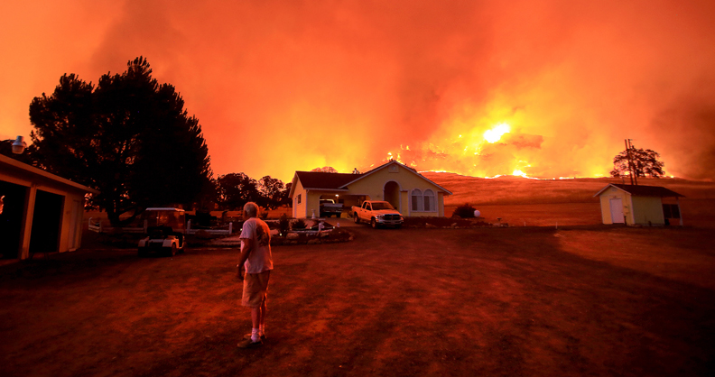 A wall of flames lurches over a ridge as a resident of Morgan Valley Road near Lower Lake prepares to evacuate the Rock Fire, Wednesday evening July 29, 2015. (Kent Porter / Press Democrat) 2015 