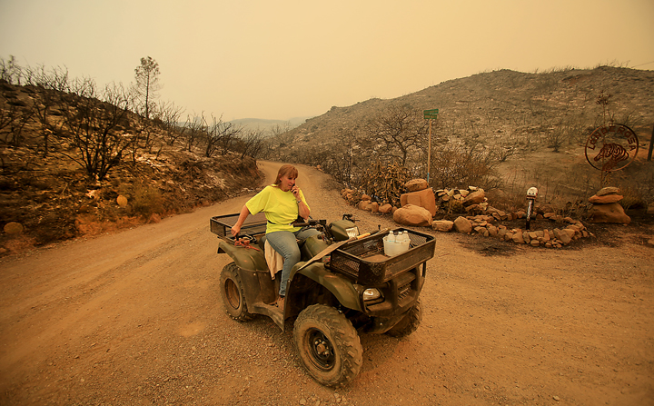 A moonscape greets Lonne Sloan at the corner of her driveway and Morgan Valley Road Thursday July 30, 2015 near Lower Lake as she calls 911 to report that fire was bearing down on her house once again. Sloan and her husband Larry stayed behind Wednesday night to put out flames around their home, even so it was touch and go, Sloan lost a barn, trailers and tractors to the Rocky Fire. (Kent Porter / Press Democrat) 2015