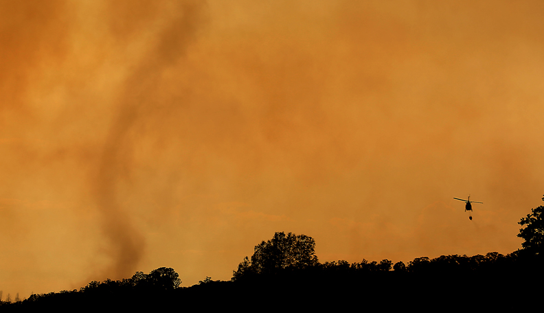 A wind driven smoke tornado dwarfs a water dropping helicopter on he Rocky fire, Thursday July 30, 2015 near Lower Lake . (Kent Porter / Press Democrat) 2015