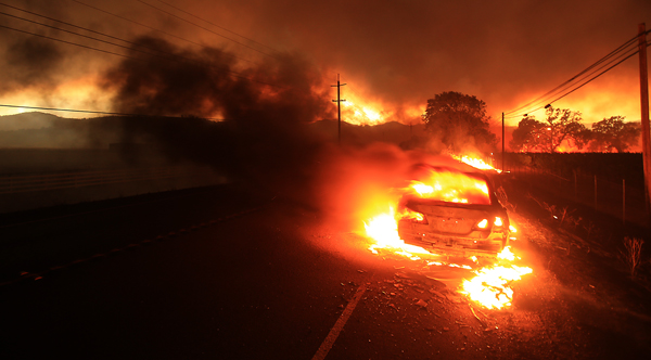 A car is engulfed in flames as the Valley fire spots over Highway 29 in Middletown, Saturday Sept. 12,  2015.  (Kent Porter / Press Democrat) 2015