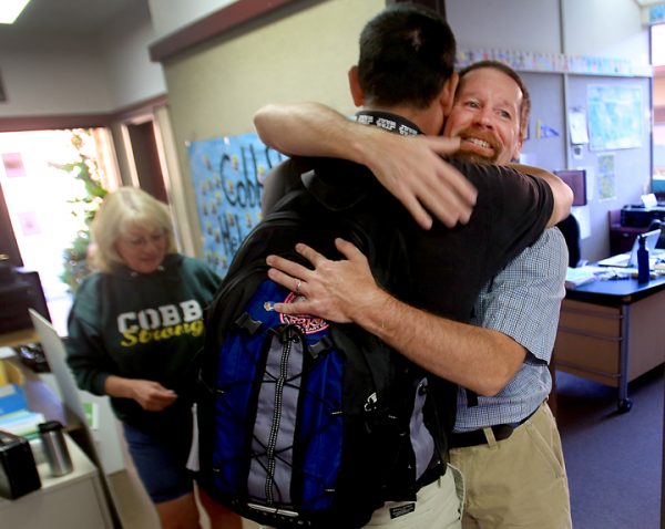 During Cobb Elementary's first day of School, Wednesday Aug. 10, 2016 principal David Leonard, right, greets sixth grade teacher Marc Moreda. Leonard lost his home to the Valley Fire a year ago. At right is school secretary Karen Huff. (Kent Porter / The Press Democrat) 2016